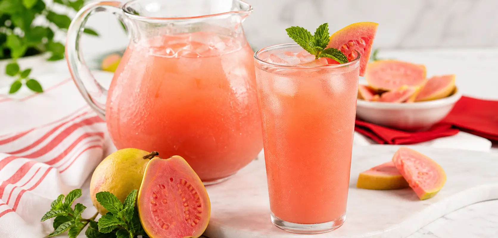 Agua fresca de Guayaba rosa con pulpa Pulpamia servida en vaso y jarra
